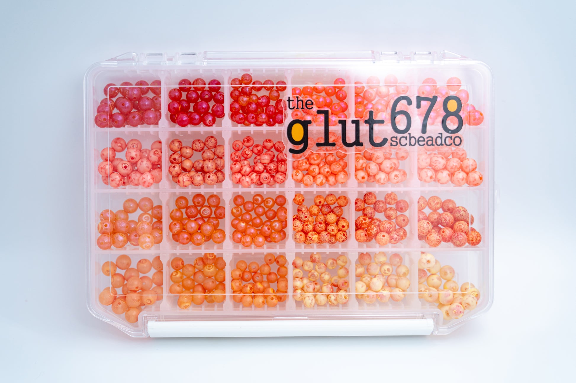 A clear plastic case containing various sizes and colors of fishing beads, organized by compartments.