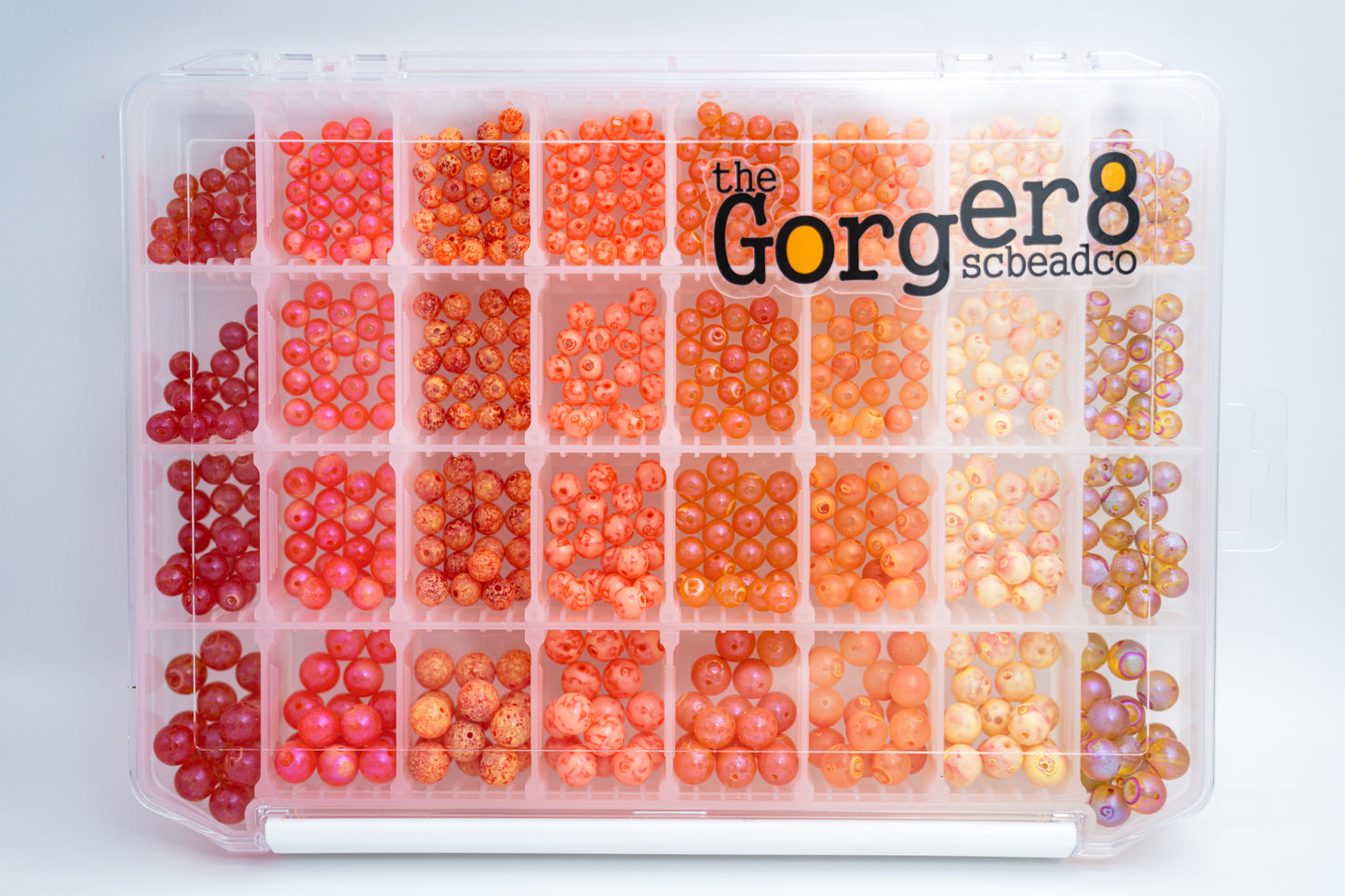 A clear plastic case containing orange and red beads in various sizes, with the text 'The Gorger8' on the top.