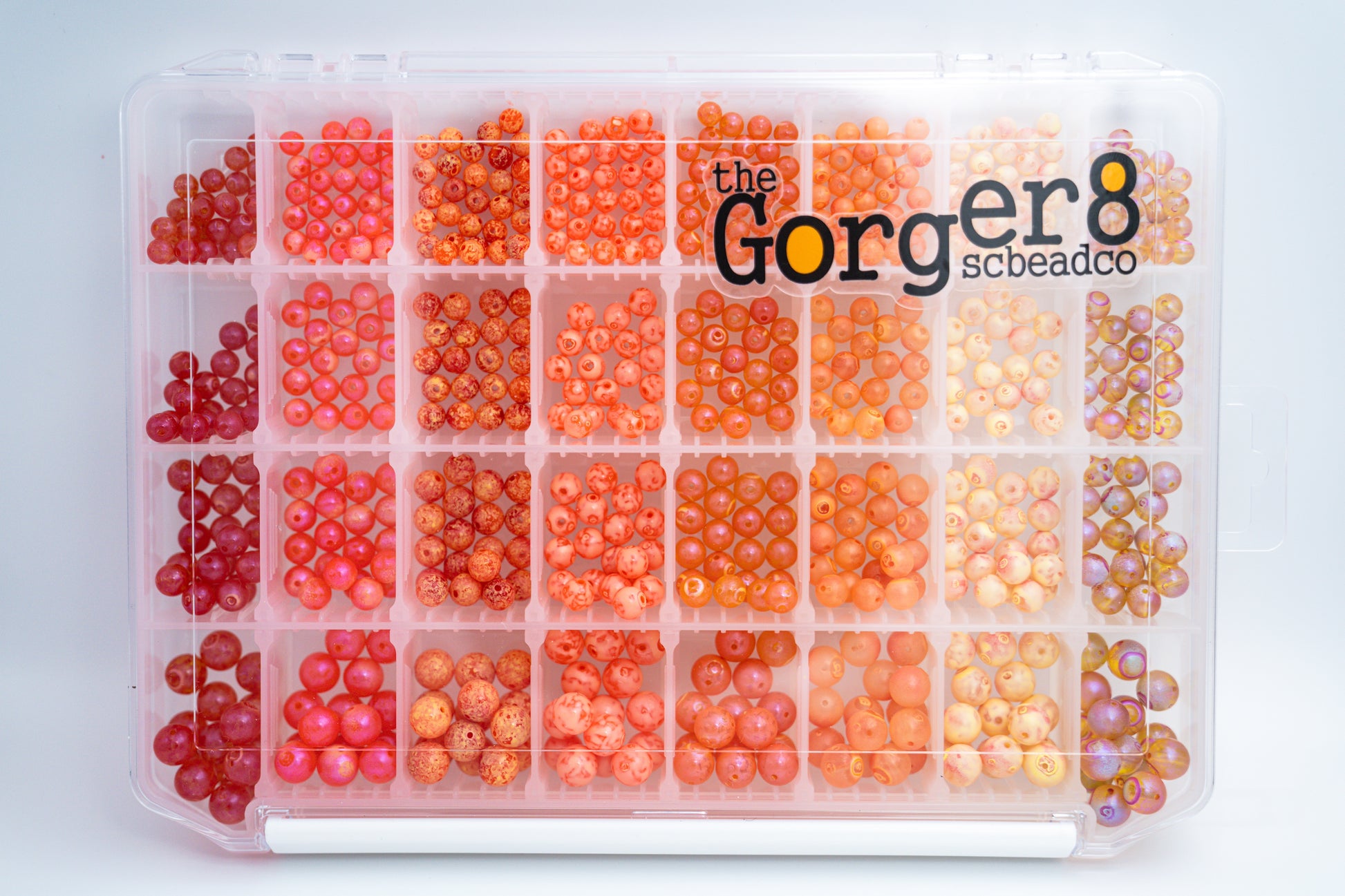A clear plastic case containing orange and red beads in various sizes, with the text 'The Gorger8' on the top.